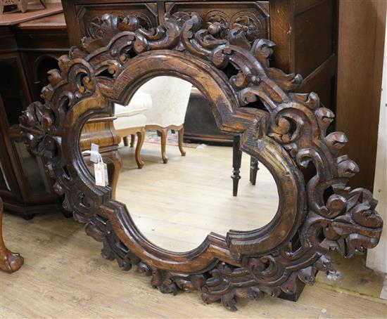 A Mexican oval wall mirror with scroll and leaf-carved frame W.86cm